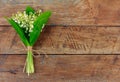 Lily of the valley flower bouquet tied with twine on wooden retro grunge background Royalty Free Stock Photo