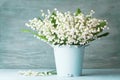 Lily of the valley flowers in blue vase on rustic table. Spring aroma bouquet