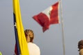 Blonde woman looking at Peruvian flag while holding Venezuelan flag