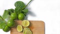 Lime, cut in half and sliced fresh citrus fruits on a wood cutting board and fresh limes on branches with green leaves Royalty Free Stock Photo