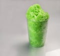 Lime green Hawaiian Shave ice, Shaved ice or snow cone dessert in a clear plastic cup.