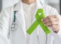 Lime green ribbon in doctorÃ¢â¬â¢s hand for Lymphoma cancer and mental health awareness, raising support and help patient living