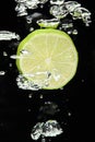 Lime (lemon) falling in water on black Royalty Free Stock Photo