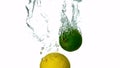 Lime and lemon plunging into water on white background