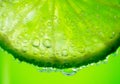 Lime slice with drop of lemon juice close-up. Fresh and juicy Citrus over green background. Dripping lime juice closeup Royalty Free Stock Photo
