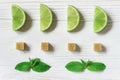Lime slices, mint and cubes of brown sugar. Ingredients for Mojito on wooden white background. Flat lay. Royalty Free Stock Photo