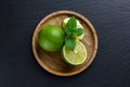 Limes with mint on wooden plate on dark stone background Royalty Free Stock Photo