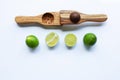 Limes with wooden lime squeezer on white