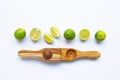 Limes with wooden lime squeezer on white