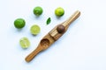 Limes with wooden lime squeezer on white