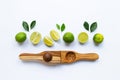 Limes with wooden lime squeezer on white