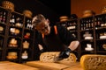 Limited maasdam cheese wheel cutting cheese in store. Cheese sommelier cuts yellow cheese wheel cut in half with a knife Royalty Free Stock Photo