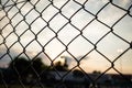 Sunrise sunset through chain link fence in bokeh background, wallpaper.