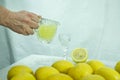 Female hand pouring a drink into a glass. Traditional homemade lemon liqueur limoncello and fresh citrus fruits on a Royalty Free Stock Photo