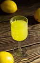Limoncello liqueur or poncha drink in a glass textured vintage glass on a wooden table with lemons Royalty Free Stock Photo