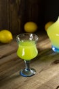 Limoncello liqueur or poncha drink in vintage glass on a wooden table with lemons and decanter with lemoncello