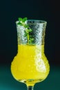 Limoncello with thyme in grappas wineglass with water drops close up on dark background, shallow depth of the field