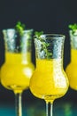 Limoncello with thyme in three grappas wineglass with water drops close up on dark background, shallow depth of the field