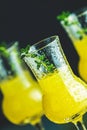 Limoncello with thyme in three grappas wineglass with water drops close up on dark background, shallow depth of the field