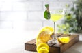Limoncello, traditional Italian liquor on a white table. Next to it is a yellow lemon, fresh citrus fruits