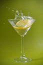 A limoncellos slice falling in a fresh cocktail, water drops on a green background Royalty Free Stock Photo