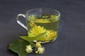 Linden flowers tea.Cup of hot herbal tea with linden fresh flowers on a black table Royalty Free Stock Photo