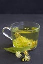 Linden flowers tea.Cup of hot herbal tea with linden fresh flowers on a black table Royalty Free Stock Photo