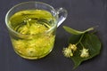 Linden flowers tea.Cup of hot herbal tea with linden fresh flowers on a black table Royalty Free Stock Photo