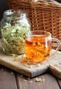 Linden herbal tea with flowers in a glass cup on wooden rustic board with lime blossom dry herb nearby Royalty Free Stock Photo