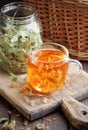 Linden herbal tea with flowers in a glass cup on wooden rustic board with lime blossom dry herb nearby Royalty Free Stock Photo