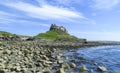 Lindisfarne Castle panoramic view from a rock beach and blue water, Holy Island, Northumberland Royalty Free Stock Photo