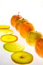 Line of apples and backlit slices with one orange Royalty Free Stock Photo