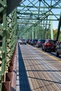 Line of automobile traffic is seen on a small two lane bridge. One lane is crowded and