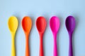 A line of bright multi-colored spoons on a blue background Royalty Free Stock Photo