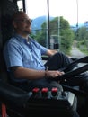 Line bus driver sitting in the driving seat with blue uniform on city bus