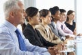 Line Of Business People Listening To Presentation Seated At Glass Boardroom Table Royalty Free Stock Photo