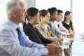 Line Of Business People Listening To Presentation Seated At Glass Boardroom Table Royalty Free Stock Photo