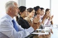 Line Of Business People Listening To Presentation Seated At Glass Boardroom Table Royalty Free Stock Photo