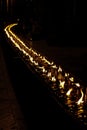 Line of candles glow in night temple