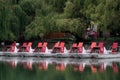 Line of catamarans with white nimbers on red part of the bodies on the water of an old park pond surrounded by green