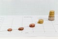 Line chart with stacked coins against background of squared paper Royalty Free Stock Photo