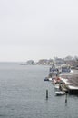 Line of colorful houses next to the harbor filled with boats on the water with a wind mill in a background