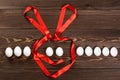 Line from Easter eggs and Easter rabbit bunny made from red scarlet ribbon are on the wooden background