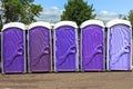 Line of Five Purple and Lavender Colored Portable Toilets