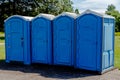 Line of Four Blue Portable Toilets