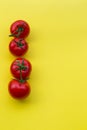 Line of four tomatoes on yellow background, copy space Royalty Free Stock Photo