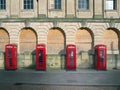 Line of four traditional british red phone boxes outside an old abandoned post office building in blackpool england Royalty Free Stock Photo