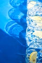 Line of Glasses of refreshing water with ice and lemon on a blue background. Heat concept, fresh. Natural light, copy space Royalty Free Stock Photo