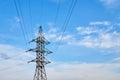 A line of high-voltage cables against a blue sky with clouds. Royalty Free Stock Photo