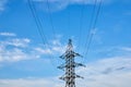 A line of high-voltage cables against a blue sky with clouds. Royalty Free Stock Photo